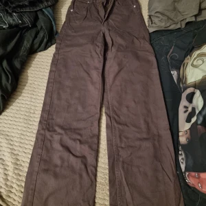 Bruna jeans - Snygga bruna jeans med hög midja och vida ben. Perfekta för en avslappnad och stilren look. Byxorna har klassiska fickor och knäppning fram.