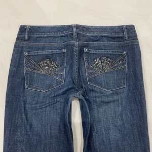 Lågmidjade bootcut jeans med rhinestones🤩 - Midja 40 cm rakt över, gren 21 cm o innerben 80 cm💕Jae 169 o xs-s o håller in pytte i midjan på bilderna. Märkta storlek 6, alltså S/liten M