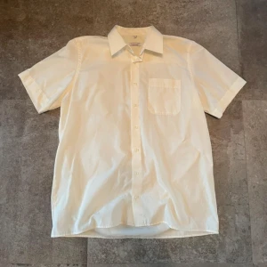 Vit/cremefärgad kortärmad skjorta - Bara använd ett fåtal gånger, mycket bra kvalitet och material. Mått: Axelbredd (52cm), längd (80cm) 