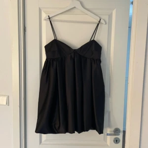 Svart axelbandslös klänning - Elegant svart klänning med smala axelband och en vacker, flytande design. Perfekt för festliga tillfällen. Enbart använd en gång! 