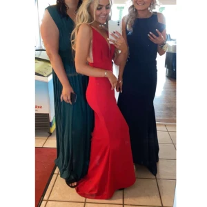 Röd långklänning - Snygg röd långklänning med djup v-ringning och smala axelband. Perfekt för bal eller festliga tillfällen. Klänningen har en elegant passform som framhäver figuren. Perfekt till bal. Tyvärr lite sliten på axelbanden men inget man tänker på.