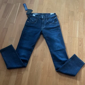 Helt nya Replay Anbass Hyperflex jeans - Snygga mörkblå Replay Hyperflex jeans med klassisk femficksdesign och kontrastsömmar. De har en bekväm passform och är tillverkade i ett stretchigt material för extra komfort. Perfekta för en stilren look. Helt nya aldrig använda, bara testade. W=27 L=32. Nypris runt 1500. Skriv till mig vid frågor eller funderingar.