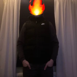 Svart dunväst från Nike - Säljer en svart dunväst från Nike med dragkedja. Västen har en stilren design och är perfekt för kyligare dagar. Den är lätt att matcha med olika outfits och ger en sportig look🔥🍾