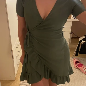 Grön omlottklänning - Snygg grön omlottklänning med volangdetaljer och knytning i sidan. Från h&m