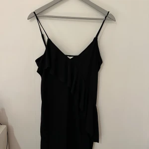 Klänning  - Svart smalbenslång klänning med volang, från Hm. Storlek M