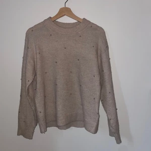 Beige stickad tröja från H&M - Säljer en beige stickad tröja från H&M med pärldetaljer för att den inte kommer till användning. Tröjan har långa ärmar och ribbstickade muddar vid ärmslut och nederkant. 💓