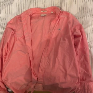 Rosa skjorta från GANT - Säljer en snygg rosa skjorta från GANT i storlek L. Skjortan har långa ärmar och knappar framtill. Perfekt för en stilren look.      Priset kan diskuteras!