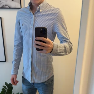 Blå och vit randig skjorta från Ralph Lauren - Säljer denna skjorta då den aldrig kommer till användning. Har använt den nån enstaka gång. Inga defekter eller liknande fortfarande nyskick! Strolek M 