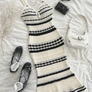 Randig stickad klänning - Snygg stickad klänning med svartvita ränder och en tight passform. Klänningen har en v-ringad design och är ärmlös, perfekt för en stilren look. Den är både bekväm och trendig, idealisk för olika tillfällen.