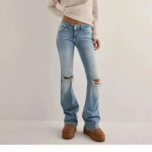 Ljusblå jeans med hål - Snygga ljusblå jeans med slitningar på knäna. De har en bootcut-stil och är lågmidjade. De är använda en gång och är i nyskick. Strl M men är väldigt stretchiga så passar för en som har strl L. Skriv för fler bilder eller frågor. Nypris:700kr