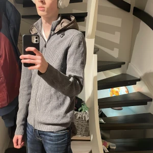 Massimo dutti cardigan - Säljer en stilren grå ribbad hoodie med dragkedja och huva. Perfekt för kyligare dagar och passar bra till jeans. Den har långa ärmar och en bekväm passform.