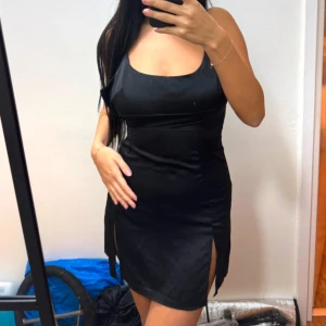 Svart klänning med slits - Snygg svart klänning med smala axelband och slits på sidan. Liten i storlek, funkar till en med mindre bröst. 