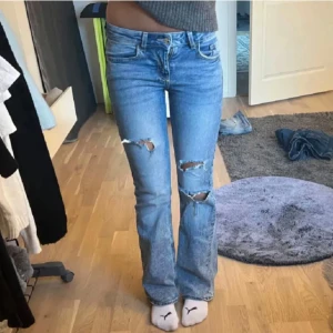 Blå lågmidjade bootcut jeans med slitningar - Snygga blå bootcut jeans med slitningar på knäna. Första bilden är lånad från hon ja köpte av❤️skriv om ni har några frågor❤️