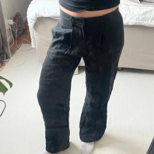 Svarta byxor i linne - Snygga svarta linnebyxor med rak passform. Perfekta för en stilren look. Byxorna har en dragkedja och knapp framtill för enkel stängning.