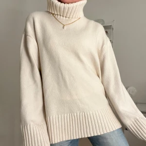 Vit stickad polotröja - Mysig vit stickad polotröja med ribbade detaljer vid ärmslut och nederkant. Perfekt för kyliga dagar med sin höga krage som håller dig varm. En klassisk och stilren design som passar till det mesta. Så trendig