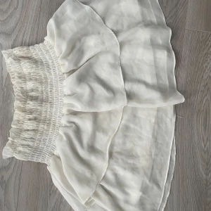 Vit kjol från Chelsea - Säljer en söt vit kjol från Chelsea med volangdetaljer och elastisk midja. Använd och har lite missfärgningar, men annars inga defekter
