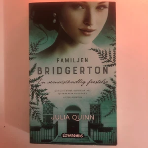 Familjen Bridgerton: En omöjlig frestelse - Säljer boken 'Familjen Bridgerton: En omöjlig frestelse' av Julia Quinn. En del av den populära Bridgerton-serien, perfekt för dig som älskar romantik och historiska romaner. Boken har ett vackert omslag med gröna och svarta detaljer. Perfekt för bokhyllan eller som present!