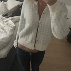 Vit och grå/blå kofta med pärlknappar - Säljer en jättesöt kofta med  långa ärmar och pärlknappar framtill. Perfekt för en elegant och mysig look. Köpt för 400 och aldrig använd, endast provad. Pris går att diskutera💞
