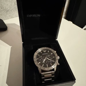  Emporio Armani klocka  - Snygg klocka från Emporio Armani med silverfärgad boett och armband. 41 mm i fint skick. 