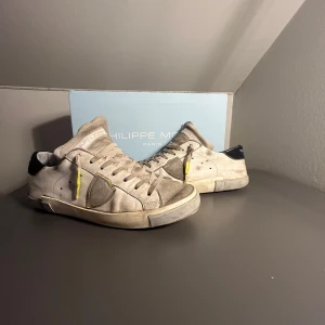 Grå sneakers från Philippe Model - Snygga grå sneakers från Philippe Model med en stilren design. I hälen på skorn så är det hål på både skorna. Perfekta för en avslappnad stil.