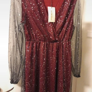 Vinröd glittrig klänning från Shein - Snygg vinröd klänning från Shein med glittrigt mönster och transparenta långa ärmar. Klänningen har en v-ringad design och är perfekt för festliga tillfällen. Den är tillverkad i ett lätt och bekvämt material som ger en elegant look.