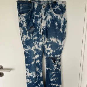 Blå och vita jeans med slitningar från YPSO - Säljer ett par unika blå och vita jeans från YPSO men köpta på loppis med coola slitningar och ett batikmönster. Jeansen har en fransig midja. De är sönder emellan benen men det är sybart har dock inte haft tid att sy. Är du villig att köpa dom me de defekterna så kan jag gå me på ett lågt pris. 