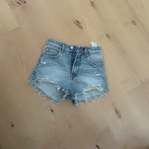 Blå jeansshorts från Zara - Säljer ett par snygga blå jeansshorts från Zara i storlek EUR 32. De har en cool, sliten look med fransiga kanter. Perfekta för sommaren och festivaler! 🕶️Säljer för att det är för små (aldrig använda)