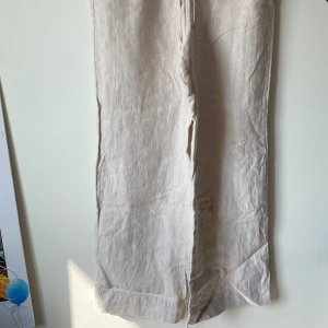 Beige linnebyxor - Säljer ett par snygga beige linnebyxor. De är högmidjade och har en avslappnad passform med breda ben. Perfekta för sommaren med sitt lätta och luftiga material. Byxorna har elastisk midja för extra komfort.