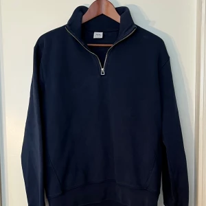 Zara Mörkblå tröja  - Säljer en stilren och bekväm mörkblå tröja från Zara. Den har en halv dragkedja framtill och en hög krage som ger en snygg look. Perfekt för vardagen.