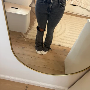 Svarta jeans med slitningar - Säljer ett par svarta jeans med coola slitningar på knäna. De har en bootcut-stil och är perfekta för en avslappnad look. Jeansen är i bra skick och passar perfekt till både vardag och fest.