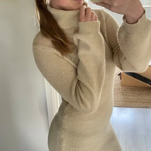 Beige stickad klänning från SHEIN - Säljer en supermysig beige stickad klänning från SHEIN. Den har en hög polokrage och långa ärmar, perfekt för kyligare dagar. Klänningen är tight och framhäver figuren på ett snyggt sätt. Perfekt för höst och vinter!