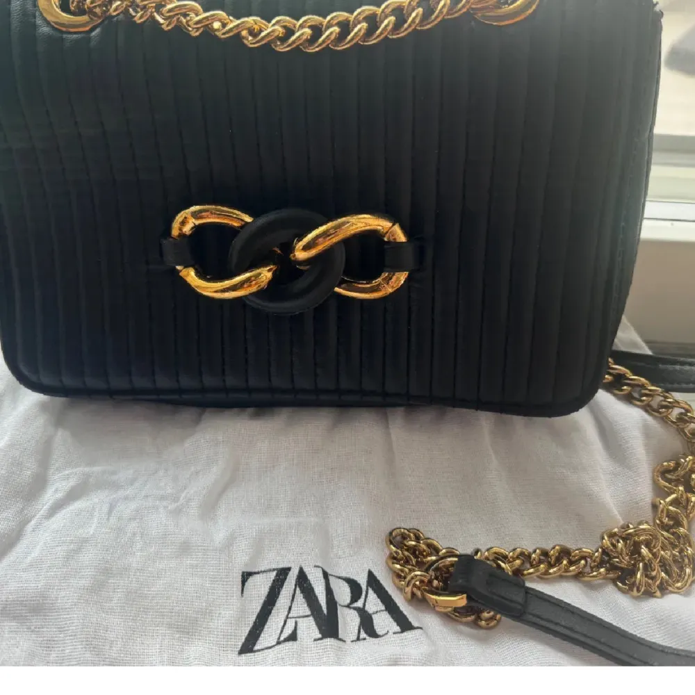 Säljer en ny superfin svart quiltad axelväska från Zara. Väskan har en elegant kedja i guld och en snygg detalj framtill. Perfekt för både vardag och fest! 🖤tygpåse tillkommer med..!. Laukut & Käsilaukut.
