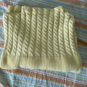 Gul stickad tröja från Cappuccini - Säljer en superfin gul stickad tröja från Cappuccini. Den har ett snyggt flätmönster på framsidan och är gjord i ett mjukt och bekvämt material. Perfekt för höst och vinter! Tröjan har långa ärmar och en normal passform. Passar både till vardags och mysiga hemmakvällar. 💛