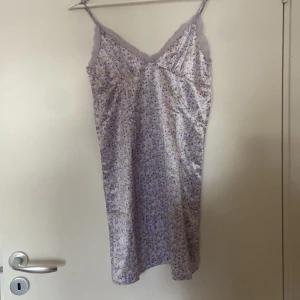 Ljuslila blommig klänning från H&M Divided - Säljer en superfin ljuslila klänning från H&M Divided i storlek XS. Den har ett sött blommigt mönster i gult och vitt, med spetsdetaljer vid halsringningen. Klänningen är ärmlös och har smala axelband, perfekt för sommarens fester eller en mysig vårdag. Materialet känns mjukt och skönt mot huden.