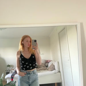 Topp med fjärilar  - Svart linne med vita fjärilar, spetsdetaljer vid brösten, smala band. 