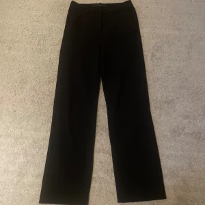 Svarta byxor från Vero Moda - Säljer ett par klassiska svarta byxor/kostymbyxor från Vero Moda. Jag skulle säga att de är midwaist och har en rak passform som ger en stilren look. Perfekta för både vardag och fest!