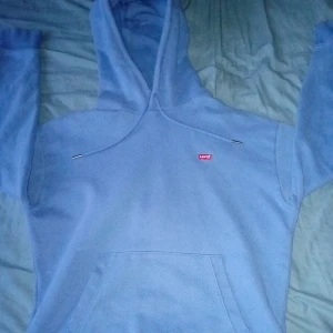 Blå hoodie från Levi's - Säljer en snygg blå hoodie från Levi's i storlek XS. Den är perfekt för en avslappnad stil och har en klassisk känguruficka framtill. Hoodien är i bra skick och superbekväm att ha på sig. Perfekt för både höst och vår!