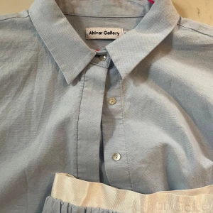 Ljusblå skjorta från Ahlvar Gallery - Säljer en stilren ljusblå skjorta från Ahlvar Gallery. Skjortan har en klassisk krage och knappar framtill. Perfekt för både vardag och festliga tillfällen. Den är i ett mjukt och bekvämt material som känns skönt mot huden.