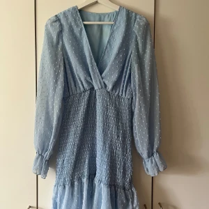 Klänning med smockdetalj - Superfin ljusblå klänning med smockdetalj som ger en fin passform. Använd fåtal gånger, passar till fest och kalas eller till vardags nu till sommaren