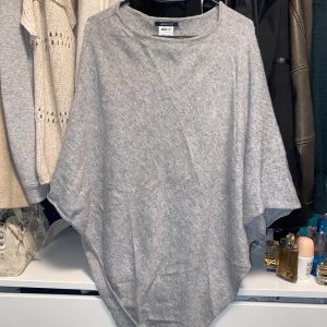 grå poncho  - grå poncho från ginatricot som använts väl, men fortfarande går att använda