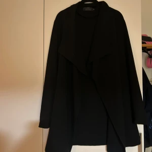 Svart kappa från ONLY - Svart knälång trenchcoat från ONLY i fint skick, storlek XS. Knappt använd och hänger bara i garderoben! 