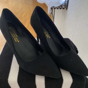 Svarta pumps med klack -  svarta pumps i mocka med spetsig tå och hög klack. Perfekt skick aldrig använda då dom är för stora för mig storlek 40