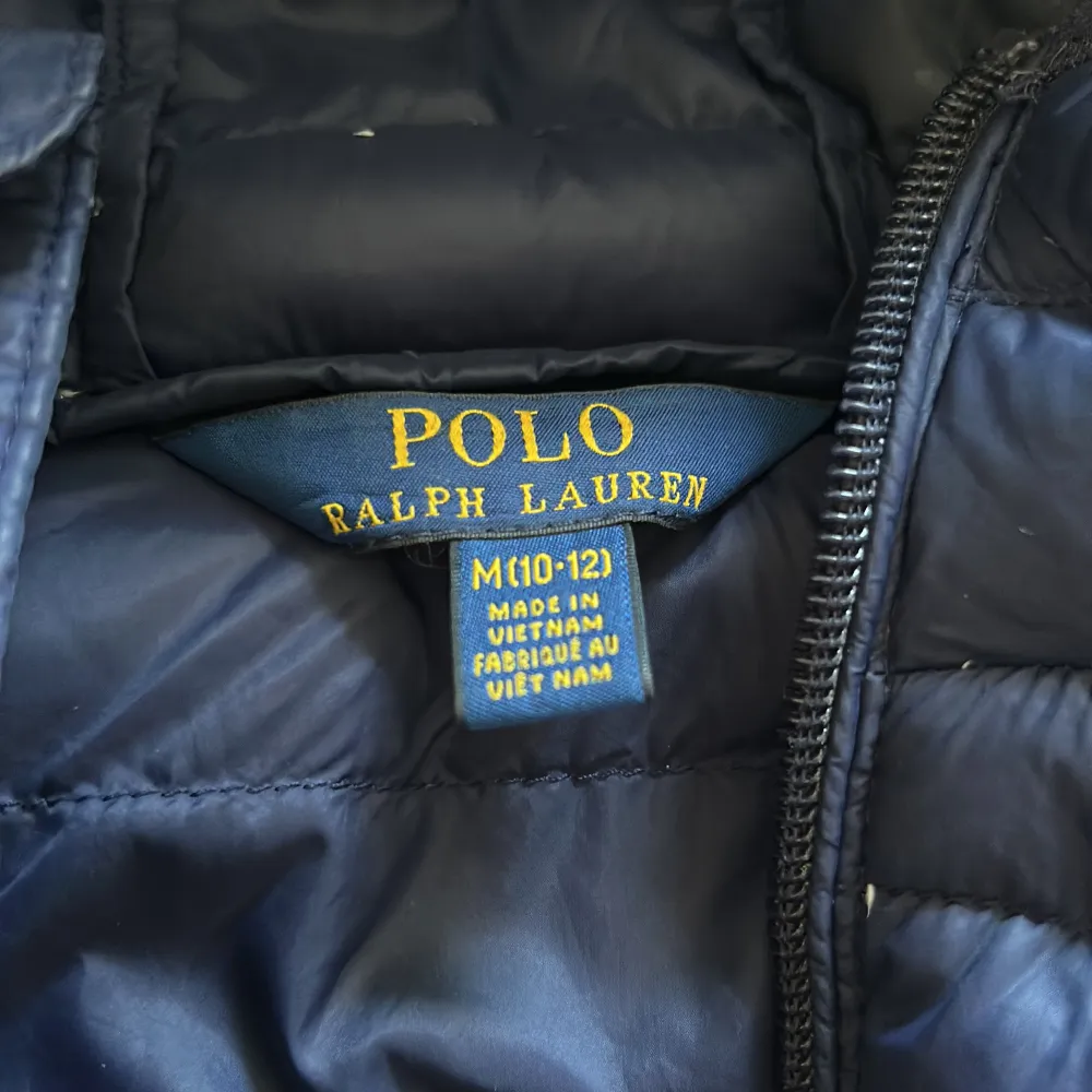 Säljer en snygg blå dunjacka från Ralph Lauren. Jackan är quiltad och har en praktisk huva. Den är perfekt för kyliga dagar och har dragkedja framtill samt fickor med dragkedjor. Jackan är i storlek M och är i bra skick.. Jackor.