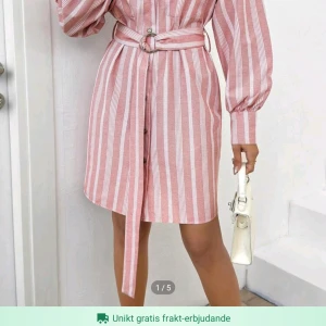 Rosa och vit skjortklänning i storlek S!  - Rosa och vit skjortklänning i storlek S!   Klänningen har slivriga knappar. Klänningen är randig och har ett skärp vid midjan.   Klönningen är helt oanvänd vilket märjs på skicket! 