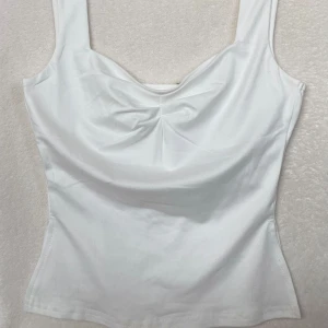 Vit topp - Vit söt topp. Toppen är rynkad vid bröstet och slits vid sidorna längst ned vid toppen som ger en söt detalj!!  Passar till alla tillfällen och är använd sparsamt🤍🤍