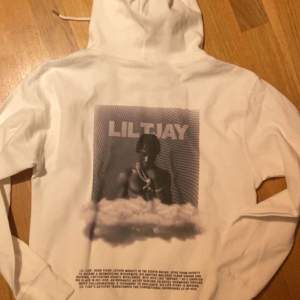 Säljer en vit hoodie med tryck av Lil Tjay. Den har en stor bild på baksidan och texten 'LIL TJAY 222' på framsidan. Perfekt för fans av Lil Tjay! Hoodien har långa ärmar och en klassisk känguruficka framtill. Den är superbekväm och stilren.