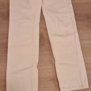 Beige byxor från Lindex - Säljer ett par snygga beige byxor från Lindex. De är en klassisk rak passform. Perfekta för både vardag och lite mer uppklädda tillfällen. Byxorna är gjorda i ett mjukt och bekvämt material.