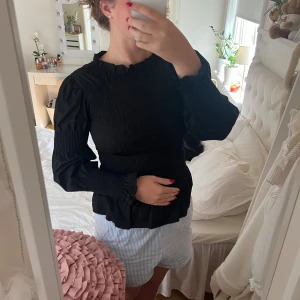 Svart blus  - Svart blus med volanger, ballongärm och textur. Från Vero Moda. Sparsamt använd och fint skick. Storlek M men är stretchig så kan passa både mindre och större. 180kr.