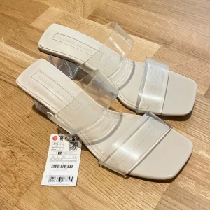 Oanvända genomskinliga klackar - Helt oanvända klackar med genomskinlig klack och remmar. Prislappen finns kvar. Inköpta på Zalando men fick aldrig användning av dem. Skorna är strl 36 och passar en smalare fot.