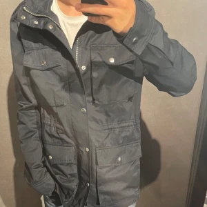 Fieldjacket marinblå  - Säljer en riktigt snygg marinblå fieldjacket i storlek xs. Skick 10/10 som ny. Modellen på första bilden är 165cm lång och jackan är lite för stor för han. Skriv om du funderar över något😊